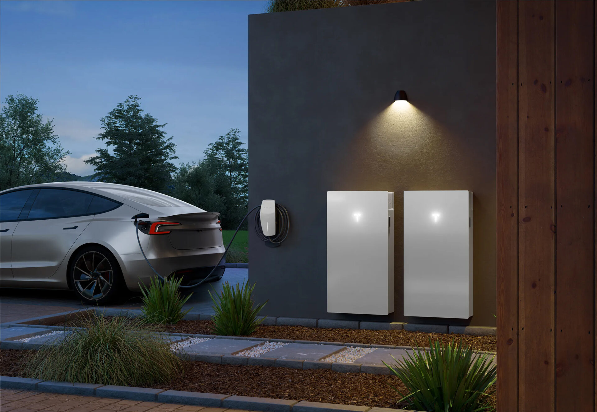 Electric car charging at a wall-mounted station beside two battery units outside a modern building, with outdoor lighting and decorative plants.